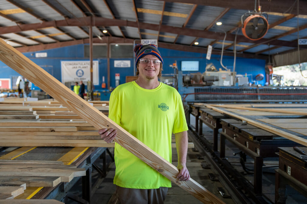 truss builder holding a piece of lumber in a truss plant